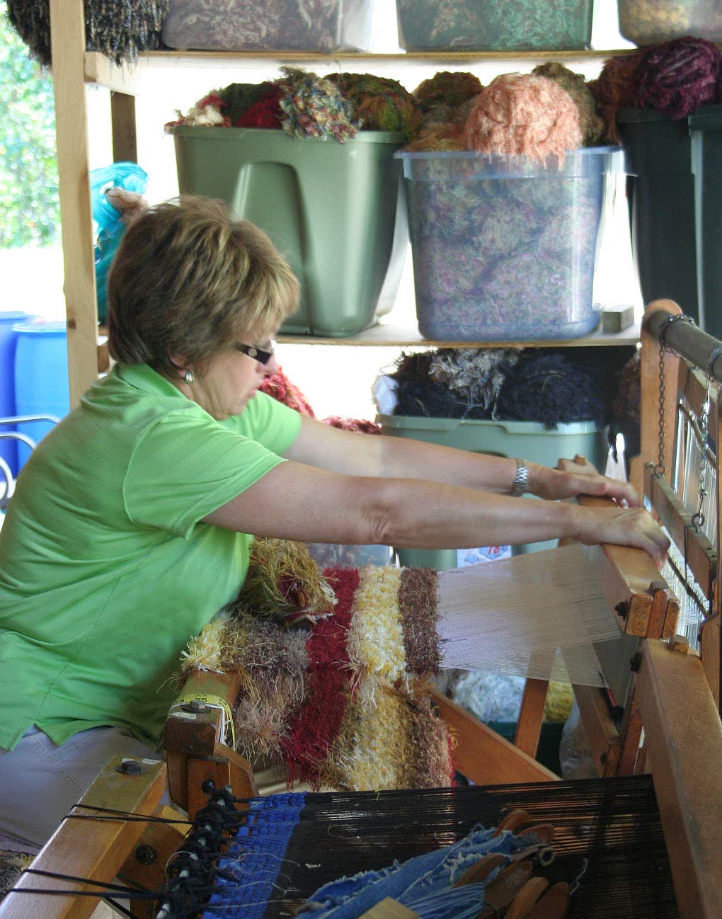A student weaving at a floor loom in the studio
