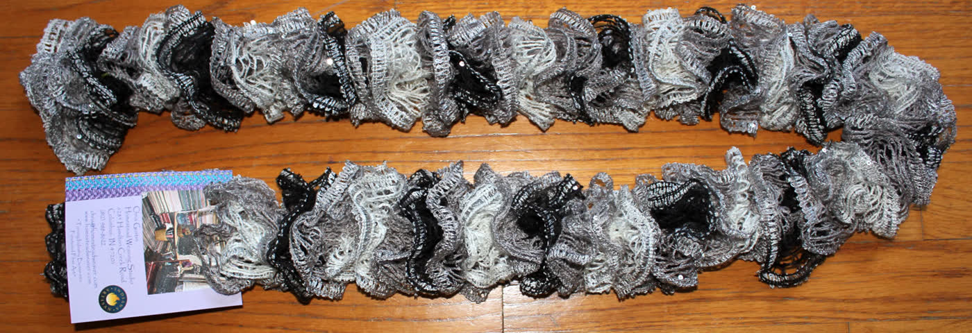 Gray ruffled scarf laid out on a wood floor