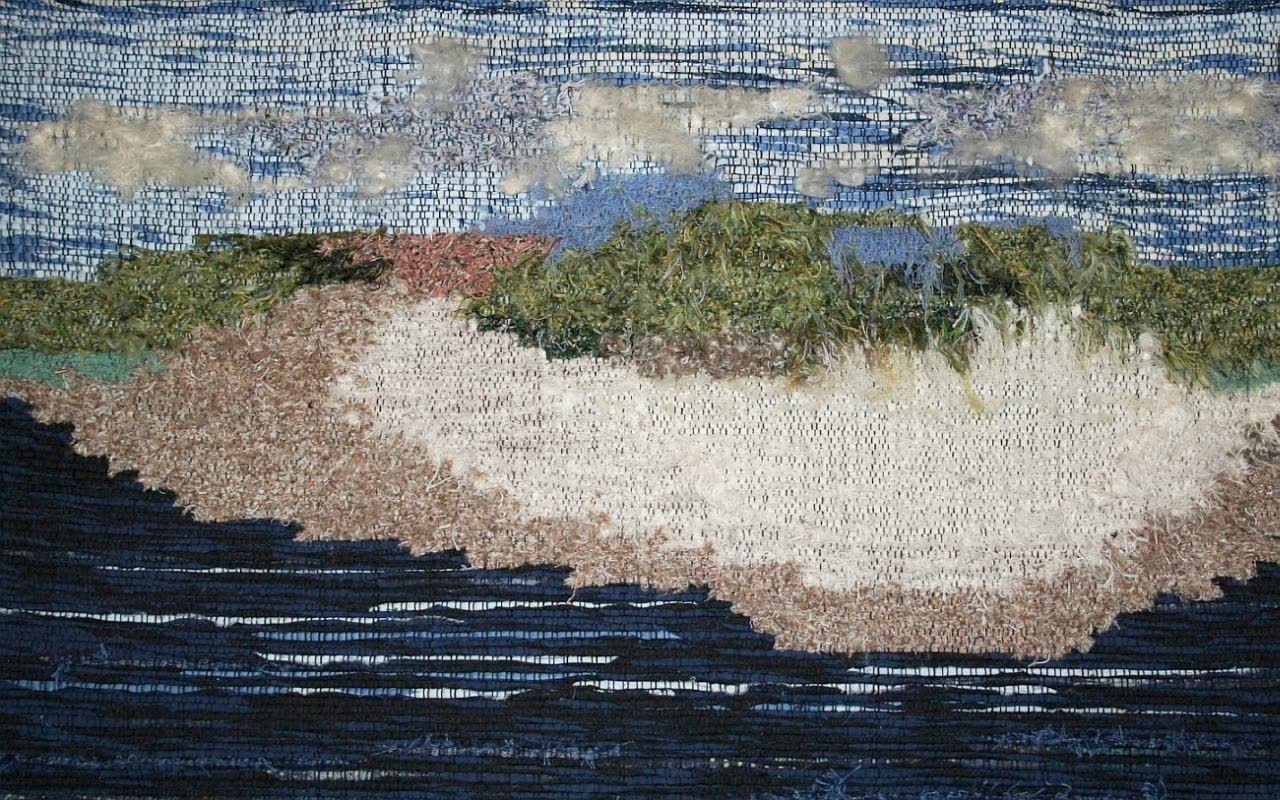 Woven wall hanging of a pale sand island in dark blue water